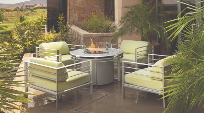 lounge chairs with green cushions around a fire table
